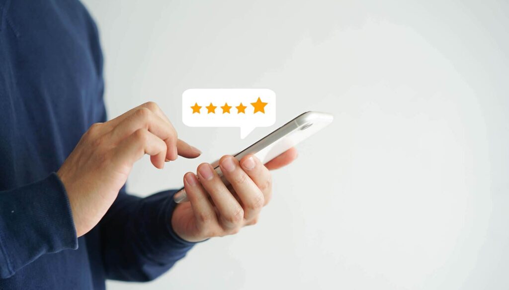 Mão segurando um smartphone que exibe um perfil otimizado do Google Meu Negócio com avaliações positivas, destacando a importância da reputação online para atrair clientes para um pequeno negócio.